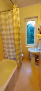 ein gelbes Badezimmer mit einer Badewanne und einem Waschbecken in der Unterkunft Лелеч in Tatariw