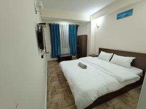 een slaapkamer met een groot wit bed en een televisie bij Snow Drop Guest House in Gangtok