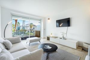 uma sala de estar com um sofá branco e uma televisão em Agence des Résidences - Appartements privés du 45 CROISETTE - Standard em Cannes