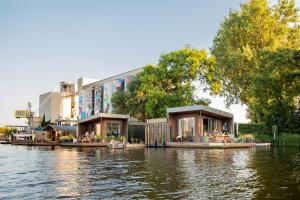 een groep gebouwen aan de oever van een rivier bij Hoteldebootel 's-Hertogenbosch met prive sauna in Den Bosch