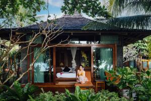 Andalay Beach Resort Koh Libong في ليبونغ: وجود امرأة جالسة أمام بيت ضيافة