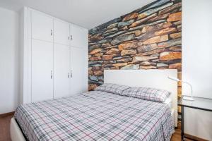 1 dormitorio con cama y pared de piedra en Diamond House Sestriere en Sestriere