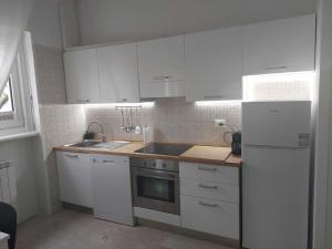 a kitchen with white cabinets and a sink and a refrigerator at Segrate San Felice in Segrate +17 photos