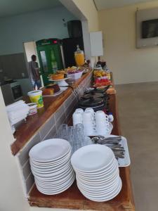 una línea de buffet con platos blancos y otros alimentos en Pousada Paraiso, en Alto Paraíso de Goiás