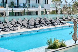 a row of lounge chairs next to a swimming pool at Mara Sea View Apartment in Năvodari
