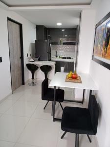 a kitchen with a white table and black chairs at Apartamento de lujo , con linda vista, cuarto piso in Cartago