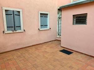 um edifício cor-de-rosa com duas janelas e piso em azulejo em CENTRAL HOME CHIOGGIA [in the historic center] em Chioggia