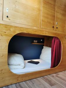 Bett in einem Zimmer mit einer Holzwand in der Unterkunft Hostel des Combes in Les Combes