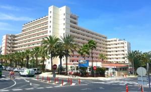 a large white building with palm trees in front of a street at Eldorado VIVIAN-STUDIO FREE WIFI in Playa de las Americas