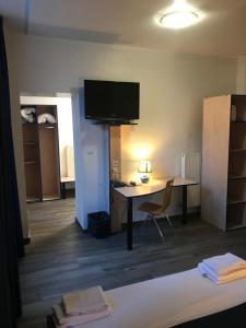 Zimmer mit einem Schreibtisch und einem TV an der Wand in der Unterkunft Cesar Hotel in Charleville-Mézières