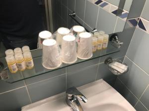 ein Badezimmer mit einem Waschbecken und einem Regal mit Pflegeprodukten in der Unterkunft Cesar Hotel in Charleville-Mézières