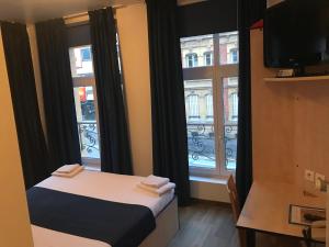 a small room with a bed and two windows at Cesar Hotel in Charleville-Mézières