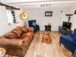 a living room with a brown leather couch and blue chairs at Pensarngerrig in Llandysul
