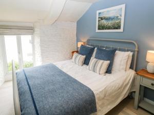 a bedroom with a bed with blue and white pillows at Alexander's Cottage in Kingsbridge