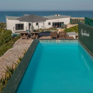 a swimming pool with a view of the ocean at Spookdraai B&B in Agulhas