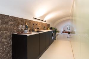 a kitchen with black cabinets and a brick wall at Wellness Apartment on the Wharf Utrecht in Utrecht +19 photos