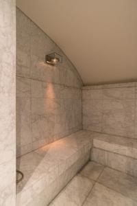 a shower in a room with marble tiles at Wellness Apartment on the Wharf Utrecht in Utrecht