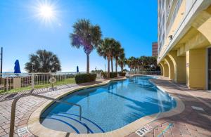 a swimming pool next to a building with palm trees at Camelot By The Sea 1206 in Myrtle Beach