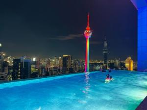 una persona en una piscina con un perfil urbano por la noche en The Platinum KLCC by Moonlight, en Kuala Lumpur