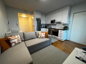 ein Wohnzimmer mit einem Sofa und einer Küche in der Unterkunft Top floor flat with sauna, A/C & free parking in Vantaa