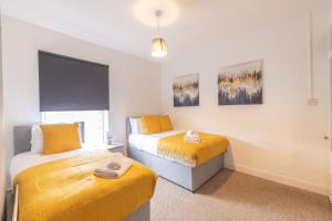 2 Betten in einem Zimmer mit gelber Bettwäsche in der Unterkunft Westminster House - Contractors/Families in Birmingham