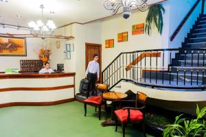 a lobby with stairs and a man standing at a counter at Hotel Oro Verde & Suites in Iquitos