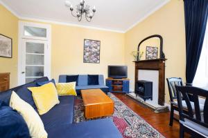 a living room with a blue couch and a tv at Edinburgh Holyrood Park Views Apartment in Edinburgh