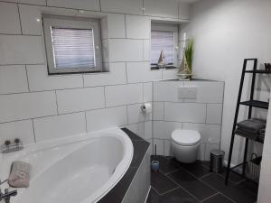 a white bathroom with a tub and a toilet at Ferienhaus Hinz in Lohe-Rickelshof