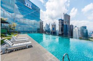 a large swimming pool with chairs and a city skyline at Dorsett Residence Kuala Lumpur 帝盛公寓 Bukit Bintang in Kuala Lumpur