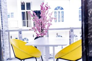 Buea的住宿－PINORICH VILLA-Buea，白色的桌子,有黄色的椅子,花瓶