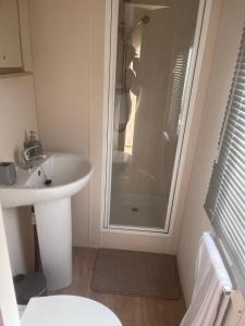 a small bathroom with a shower and a sink at LillyPad Caravan in Selsey