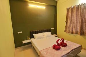 Un dormitorio con una cama con dos rosas rojas. en Picaddle Serviced Apartment en Belgaum