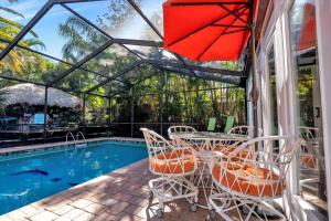 a patio with a table and chairs next to a pool at Sneaky Tiki: Heated Saltwater Pool+5 min to beach in Largo