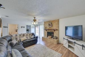 sala de estar con sofá de cuero negro y TV de pantalla plana en Charming Fort Worth Retreat about 12 Mi to Dtwn! en Fort Worth