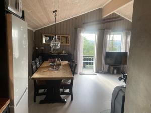 uma sala de jantar com uma mesa com cadeiras e uma televisão em Hytte med Anneks og fantastisk utsikt på Ljøsheim em Mesnali