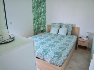 - une chambre avec un lit et une couette verte et blanche dans l'établissement Casita: votre oasis de détente, à Sérignan