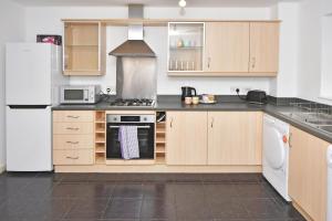 uma cozinha com armários de madeira e um forno com placa de fogão em Tansey House by YourStays em Newcastle under Lyme
