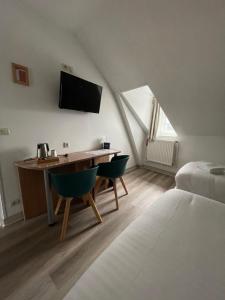 a room with a desk with two chairs and a bed at Hôtel Du Commerce in Fécamp