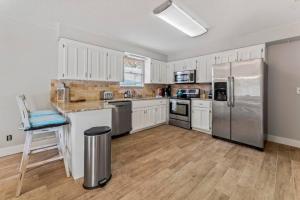 a kitchen with white cabinets and a stainless steel refrigerator at Saltwater Oasis - Large Pool in Jacksonville Beach