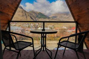 a table and two chairs on a balcony with a view at Peak view kazbegi in Stepantsminda