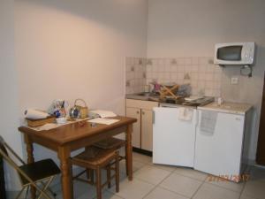 a small kitchen with a table and a white refrigerator at Clos des plages studio avec parking privatif in La Ciotat