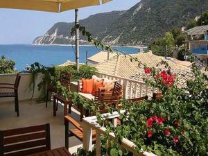 a patio with chairs and an umbrella and the ocean at Ionis Hotel in Agios Nikitas
