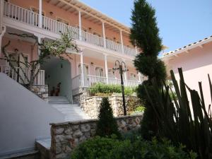 a large pink building with stairs and plants at Ionis Hotel in Agios Nikitas