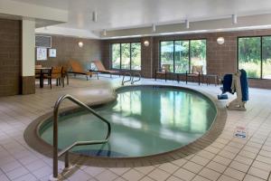 a large swimming pool in a hotel lobby with tables and chairs at Courtyard Binghamton in Vestal