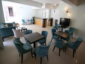 a waiting room with tables and chairs and a tv at Ionis Hotel in Agios Nikitas