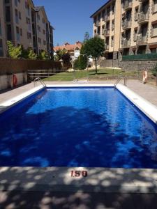 a large blue swimming pool in front of some buildings at Vivienda reformada con GARAJE, PISCINA y WIFI in Jaca