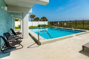 a swimming pool with two lounge chairs next to it at Sandpiper Oceanfront 5C in Jacksonville Beach