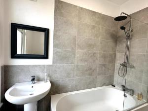 W łazience znajduje się umywalka, wanna i lustro. w obiekcie Middleton House by Blue Skies Stays w mieście Hartlepool