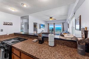 a kitchen with a stove and a living room with the ocean at Sandpiper Oceanfront 5C in Jacksonville Beach