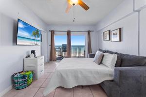 a bedroom with a bed and a couch and a balcony at Sandpiper Oceanfront 5C in Jacksonville Beach